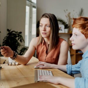 Woman and boy collaborate at a desktop computer in a bright office space.
